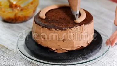 特写：饼干奶油以螺旋的形式出现在蛋糕上.. 巧克力海绵蛋糕加奶油。 准备蛋糕